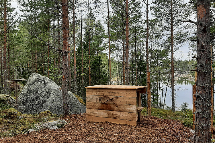 Pilgrimskyrkan och -stigen Altare i skogen, vatten som bakgrund.