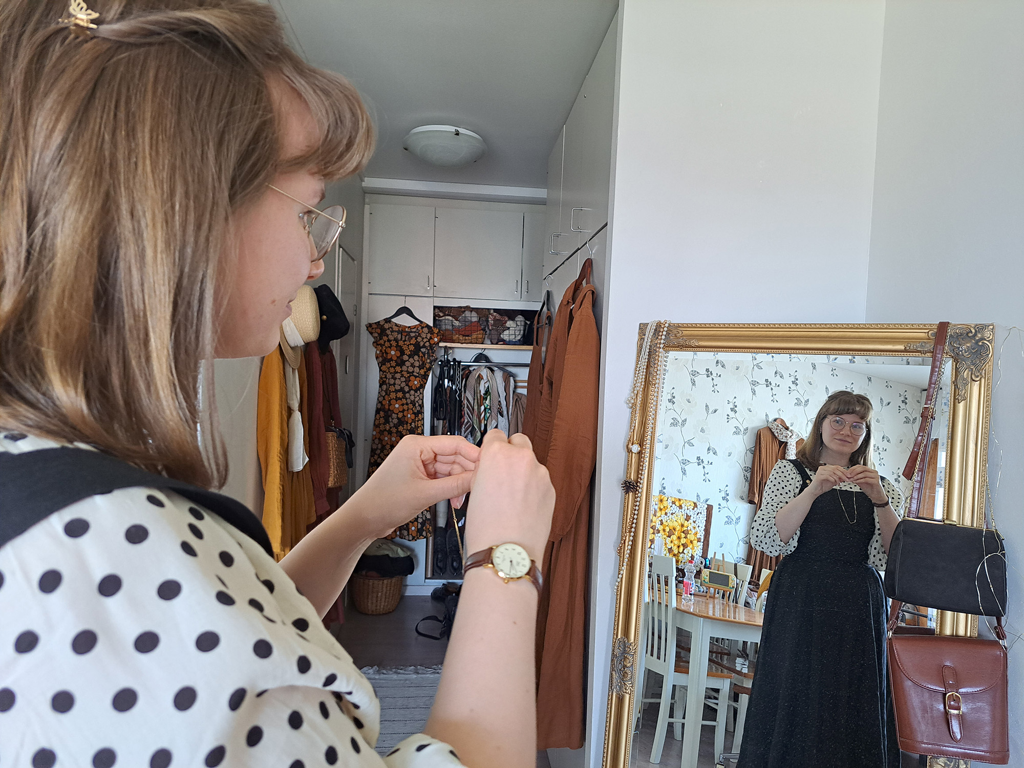 Kvinna sätter på sig ett halsband famför en spegel.