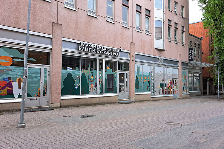 Rosafärgat rappat hus med stora fönster med färglada tejpningar i en gränd.