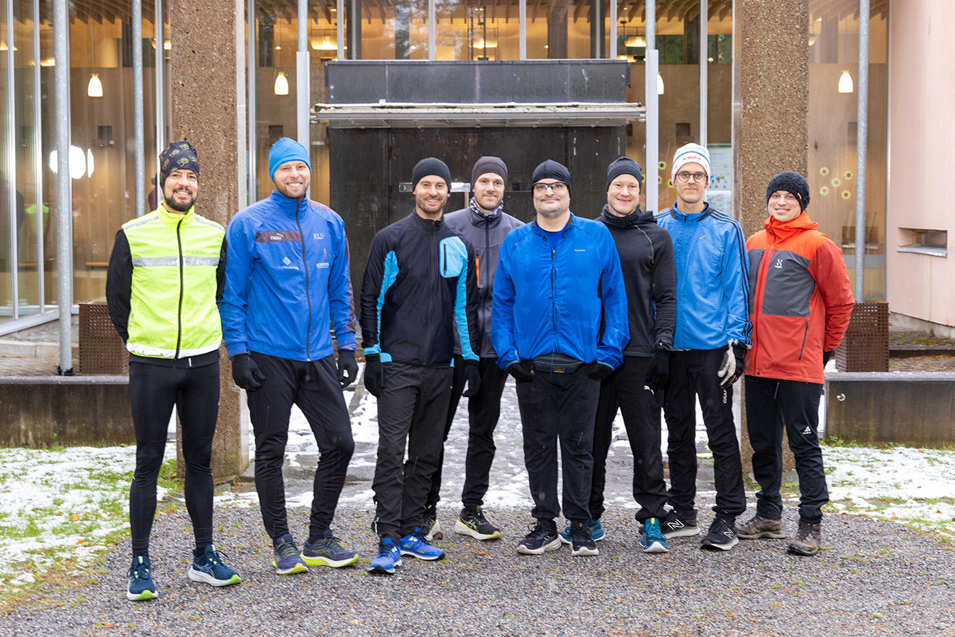 En grupp med sportklädda män står framför en byggnad.
