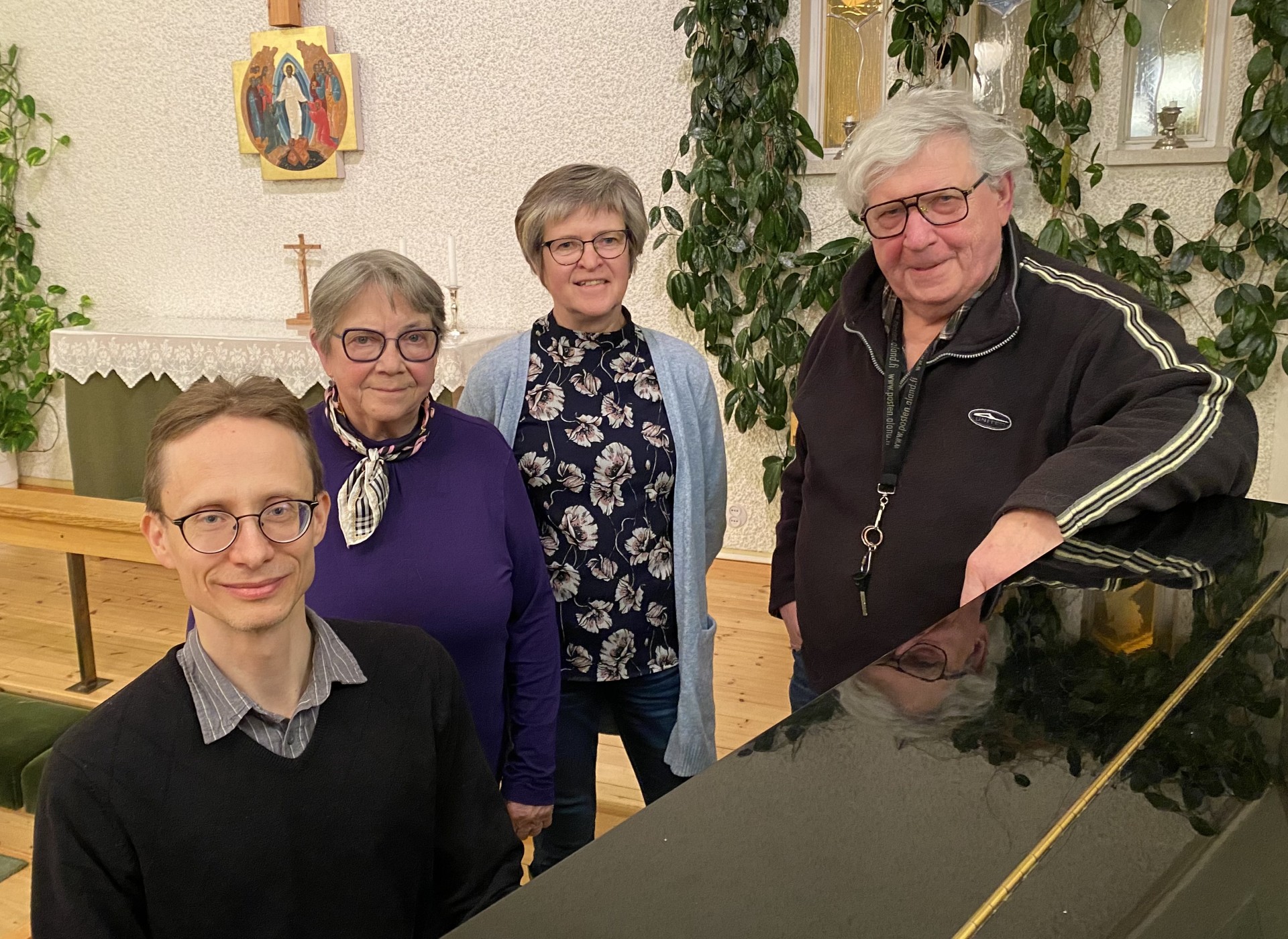 Fyra personer framför en flygel i en kyrka.