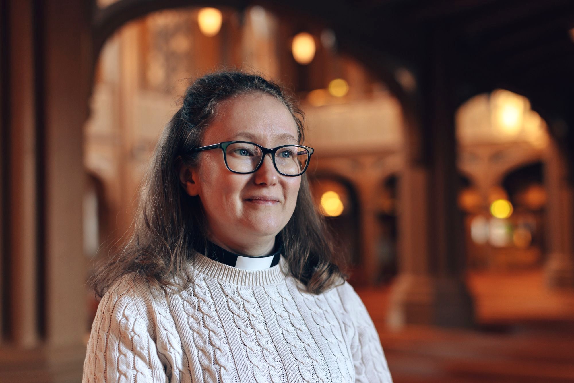 Kvinna med prästkrage i en kyrksal.