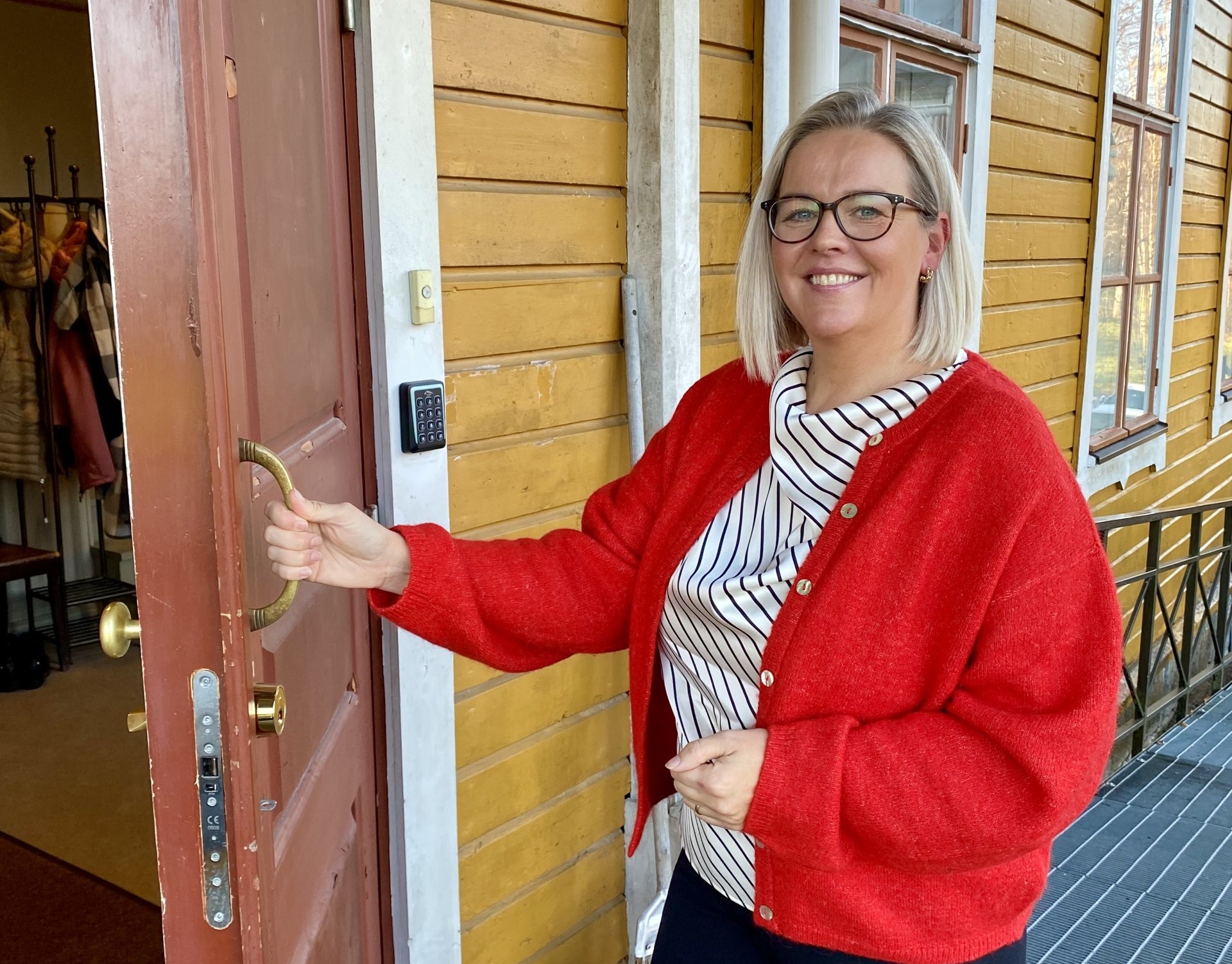Ramona Finnila öppnar en ytterdörr till en gul träbyggnad.