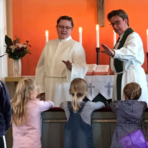 En präst och en assistent välsignar skolelever 
