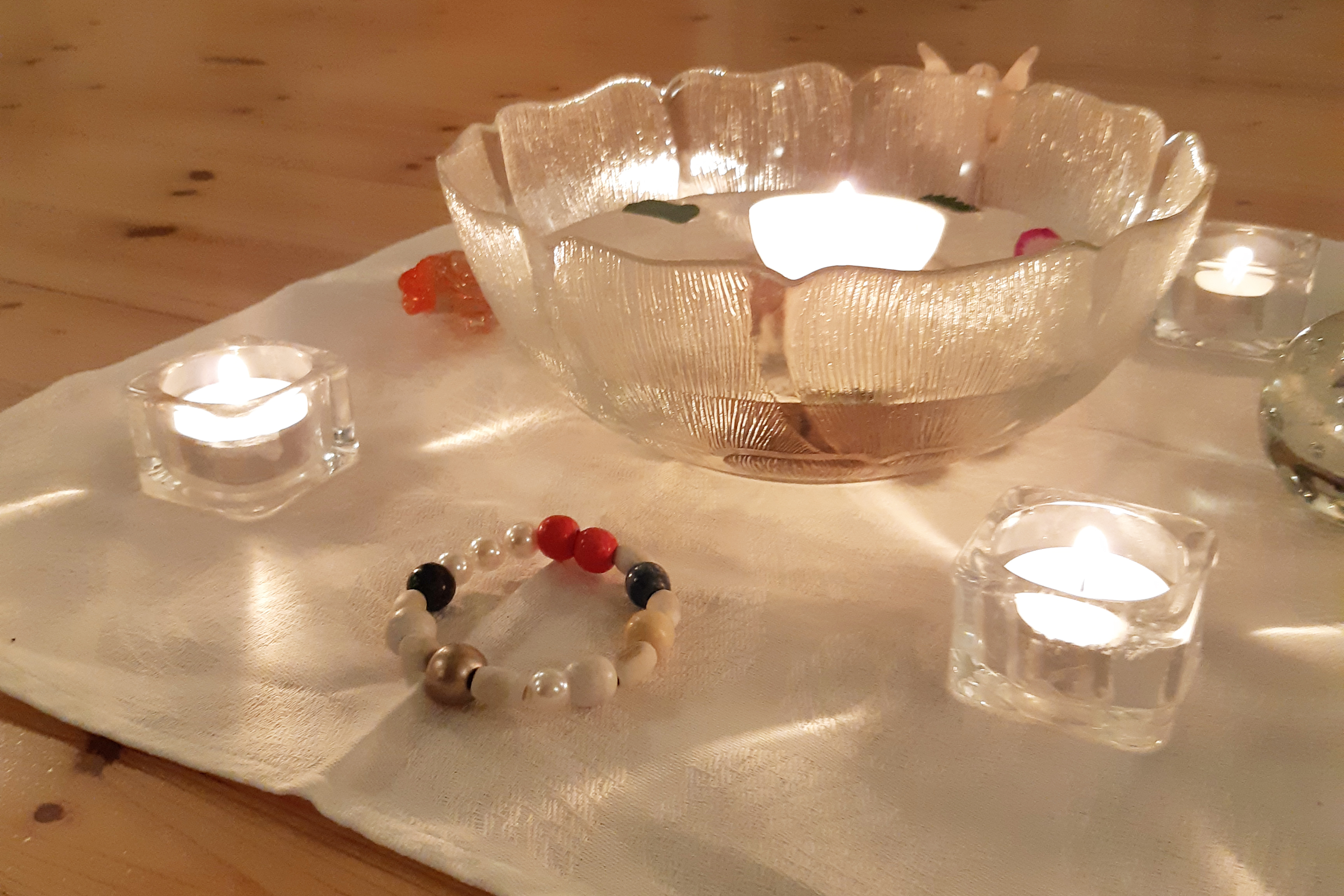 Dans i Heligt rum Skål med vatten på ett golv. Brinnande ljus och ett armband.