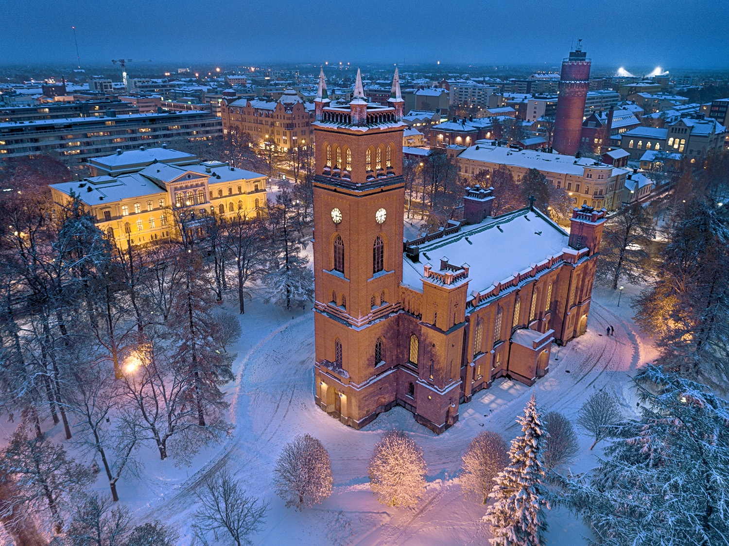Julkonserten Stilla natt, Heliga natt – Jouluyö, Juhlayö på Youtube Upplyst röd tegelkyrka uppifrån sett. På marken finns lite snö.