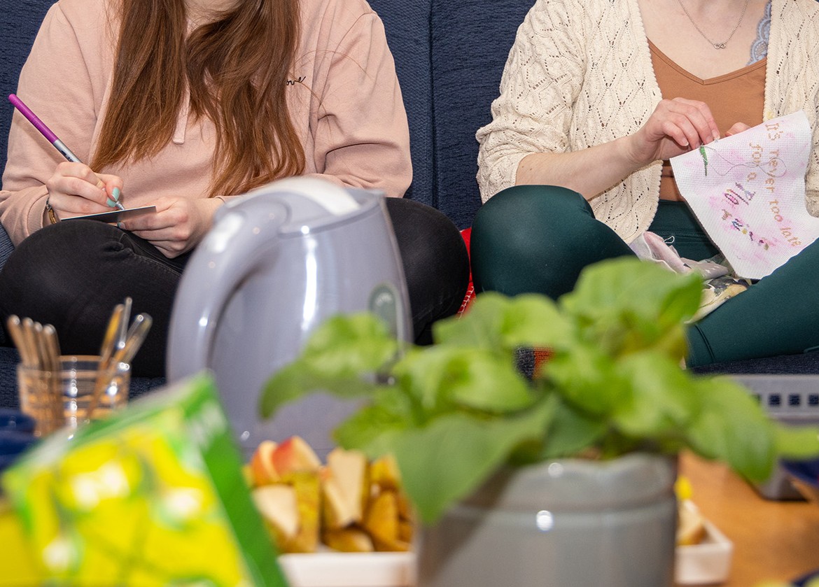 Två personer sitter och handarbetar. 