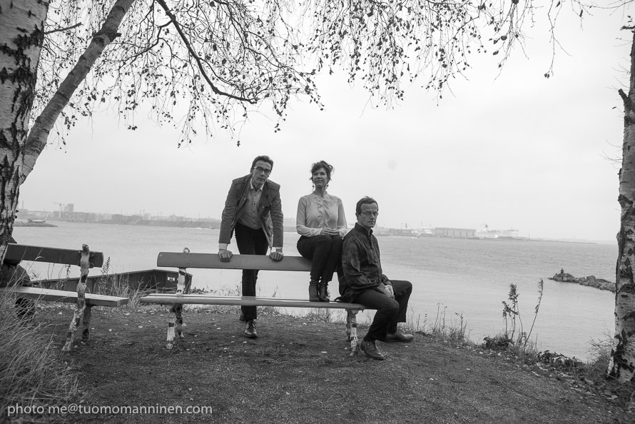 Aftonmusik Tre personer sitter och står kring en bänk. I bakgrunden syns havet.