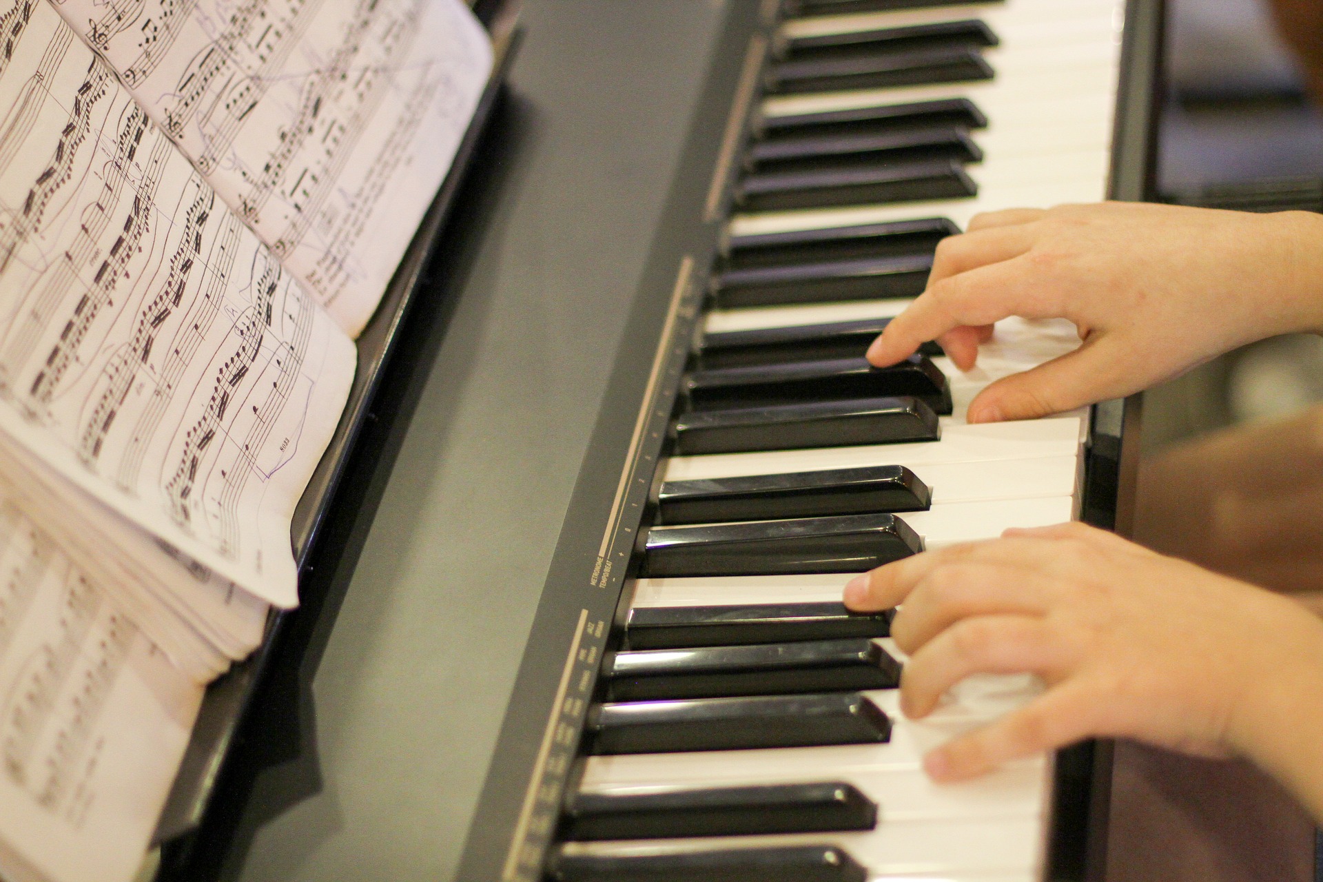 Anmälan till musikskolan Händer syns på ett pianos tangentbord.