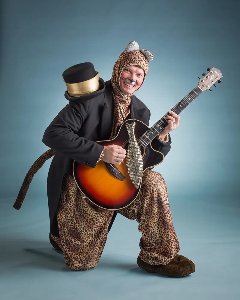 Man utklädd till katt håller i en gitarr.