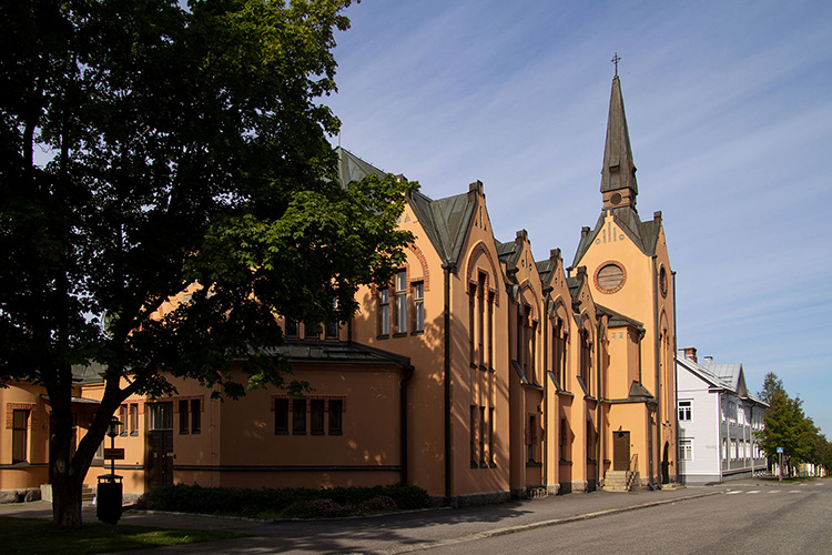 Gulorange rappad kyrka med brunt plåttak.