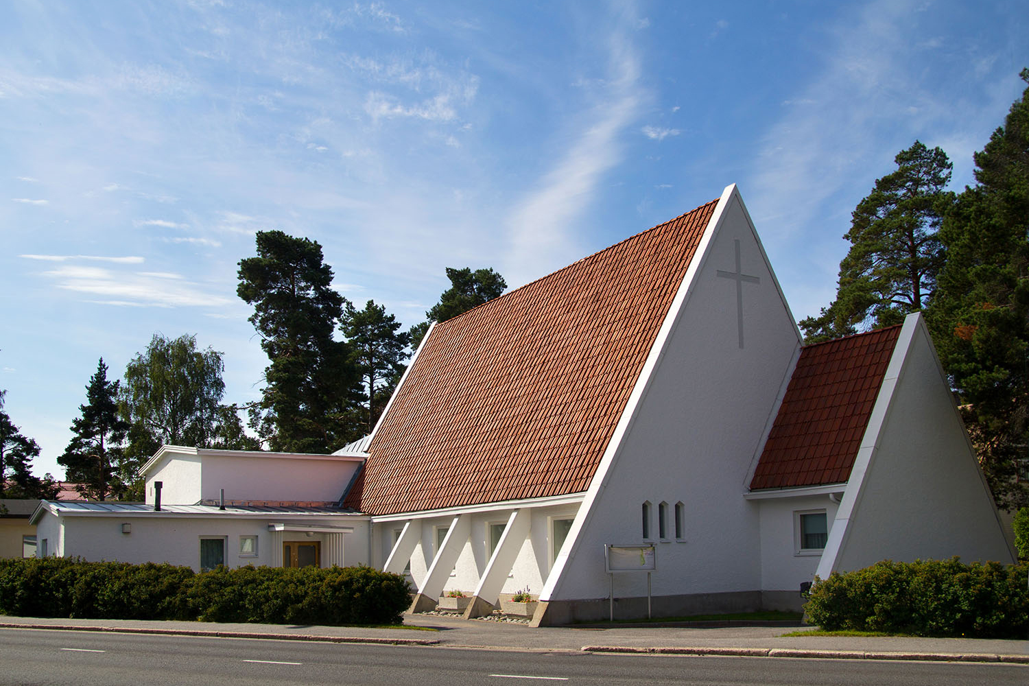 Vit triangelformad kyrka med rött tegeltak