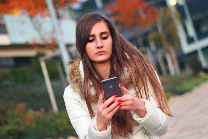Kvinna som håller i en telefon. Länk till församlingens webbsida med info om vårt samtalsstöd.