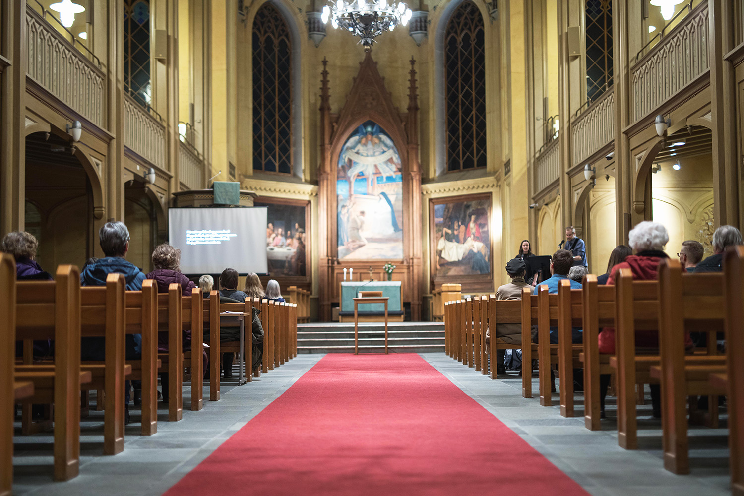 Människor som sitter i kyrkbänkar bakifrån sett.