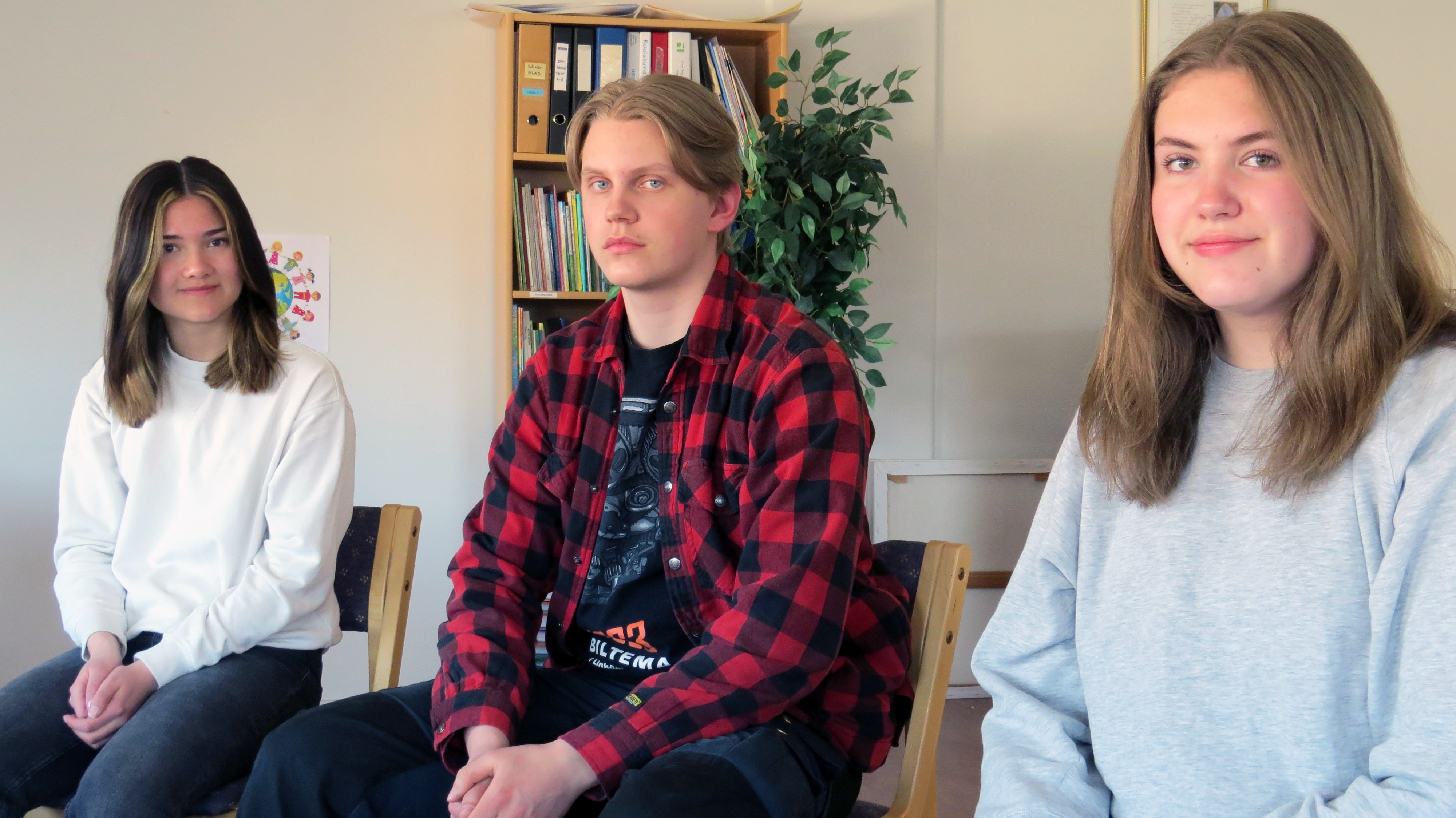 Tre ungdomar sitter bredvid varandra.
