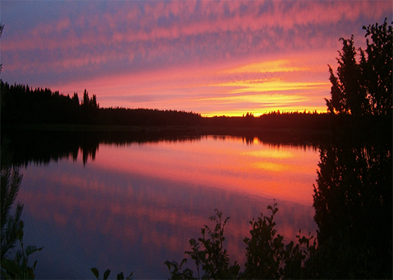 Solnedgång över en sjö en sommarkväll.