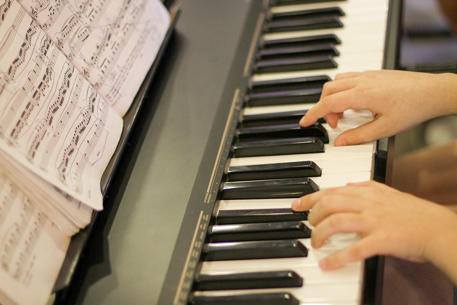 Händer syns på ett pianos tangentbord.