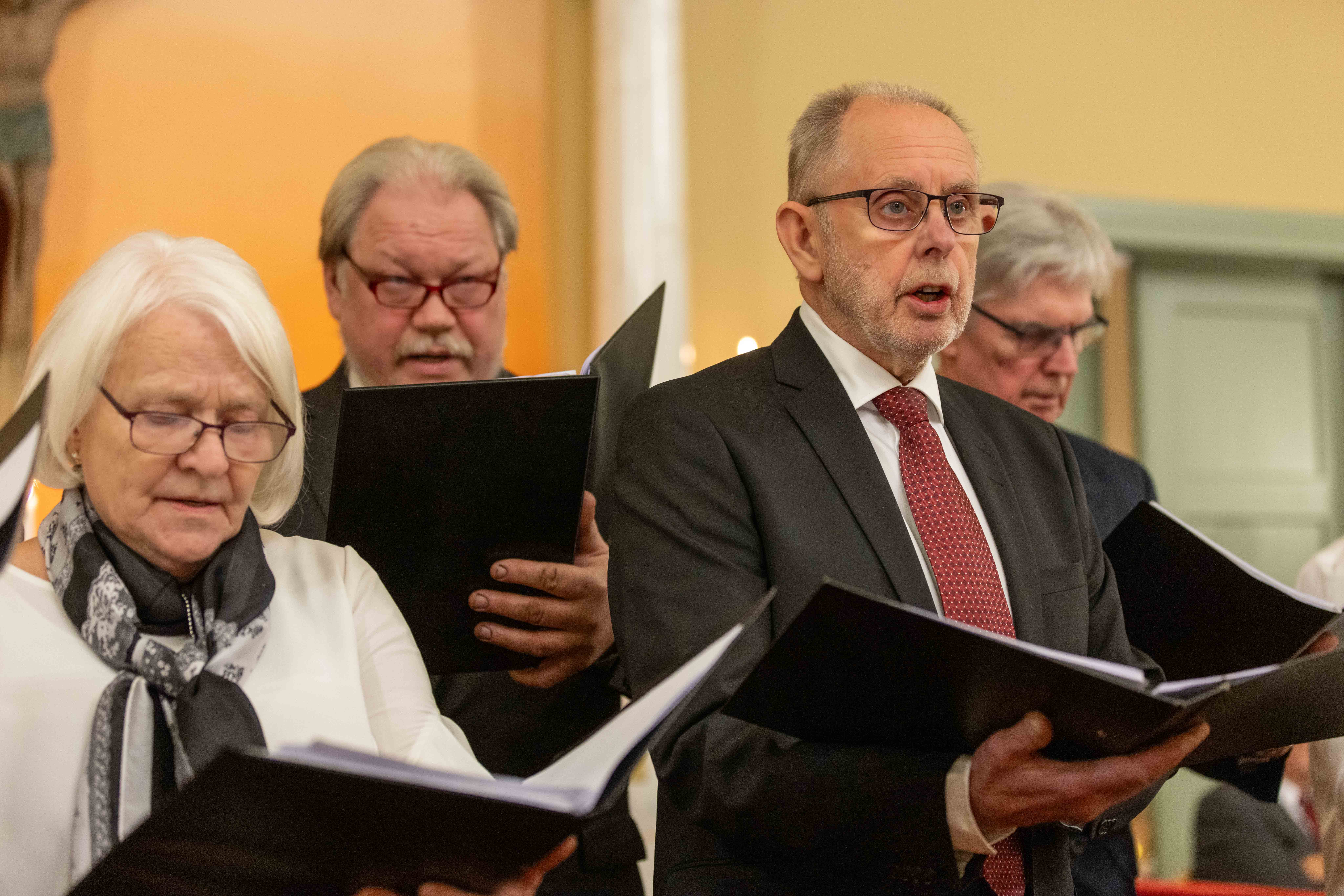 Tre män och en kvinna sjunger i en kyrka.