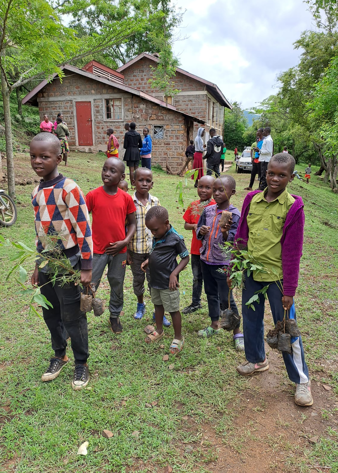 Barn och ungdomar i Kenya håller trädplantor i sina händer.