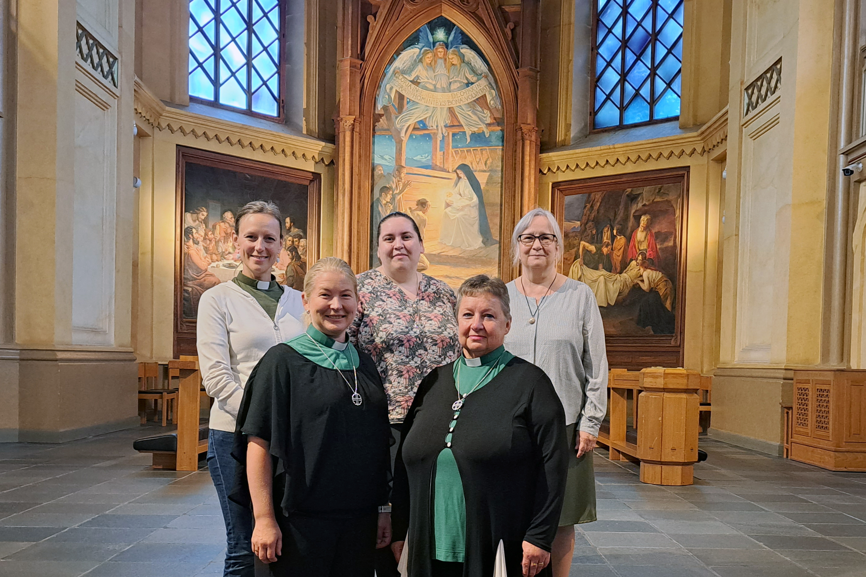 Fem kvinnor står framför altaret i en kyrka.