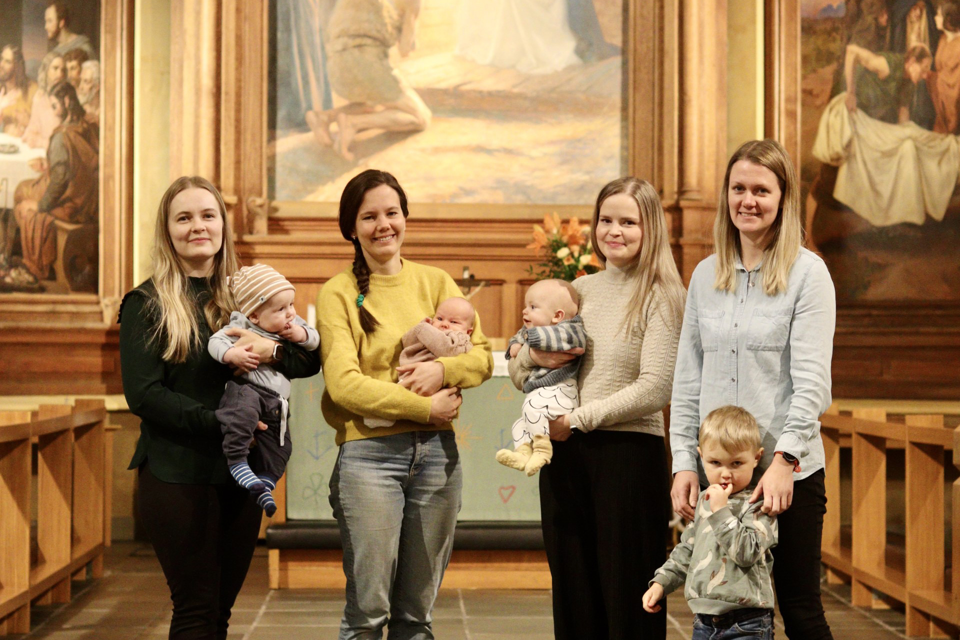 Fyra kvinnor och barn framför altaret i en kyrka.