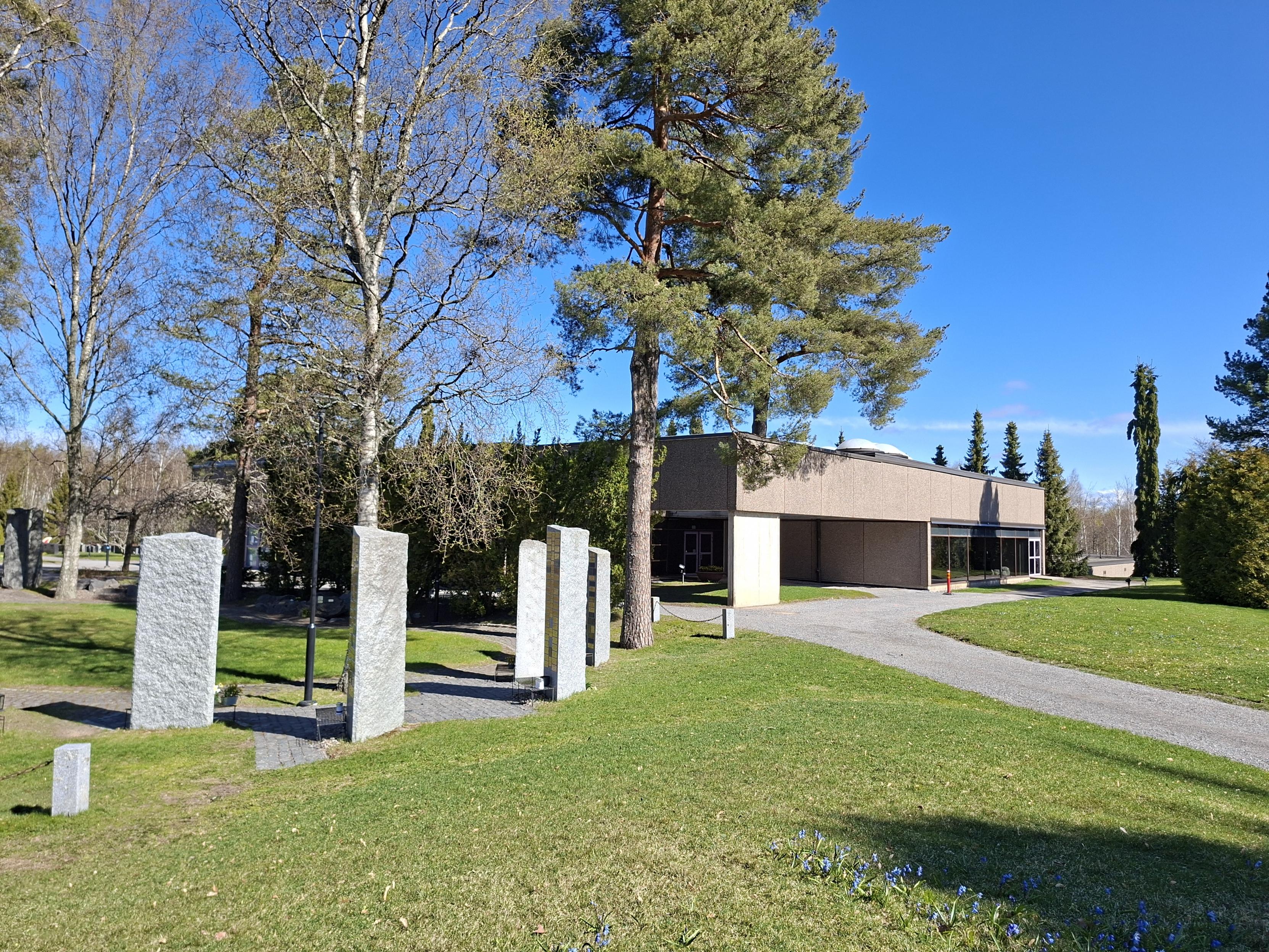 Rödgrå byggnad i park.