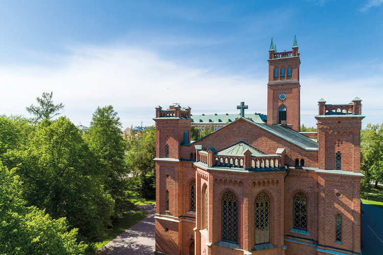 Trefaldighetskyrkan snett utifrån så att korset på taknocken syns. I bakgrunden kyrktornet.