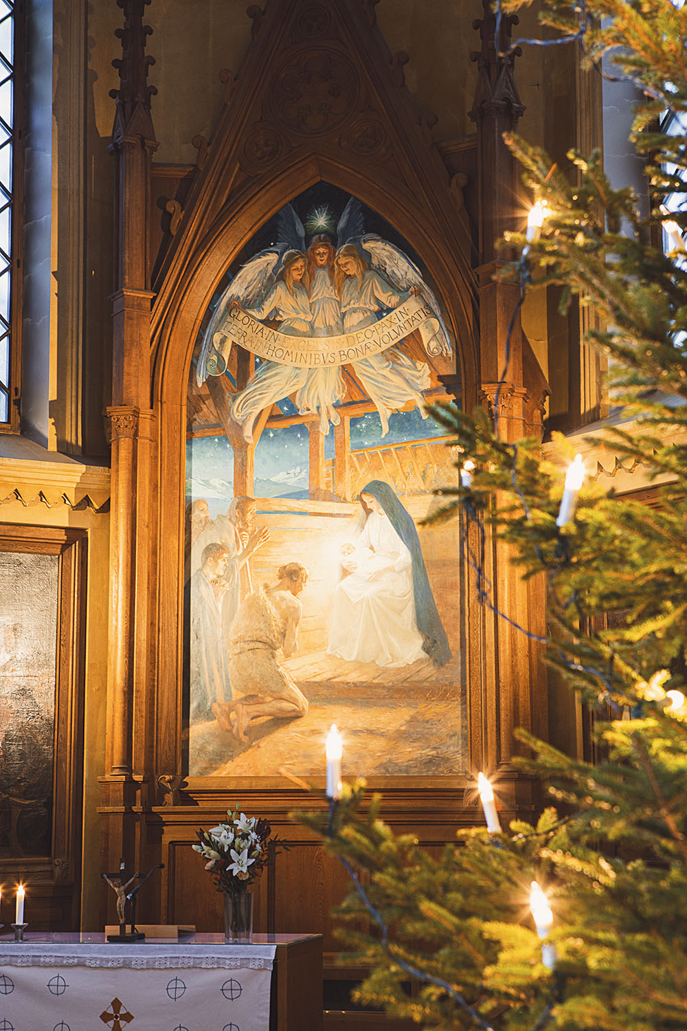 Julgran och altartavla i en kyrka.