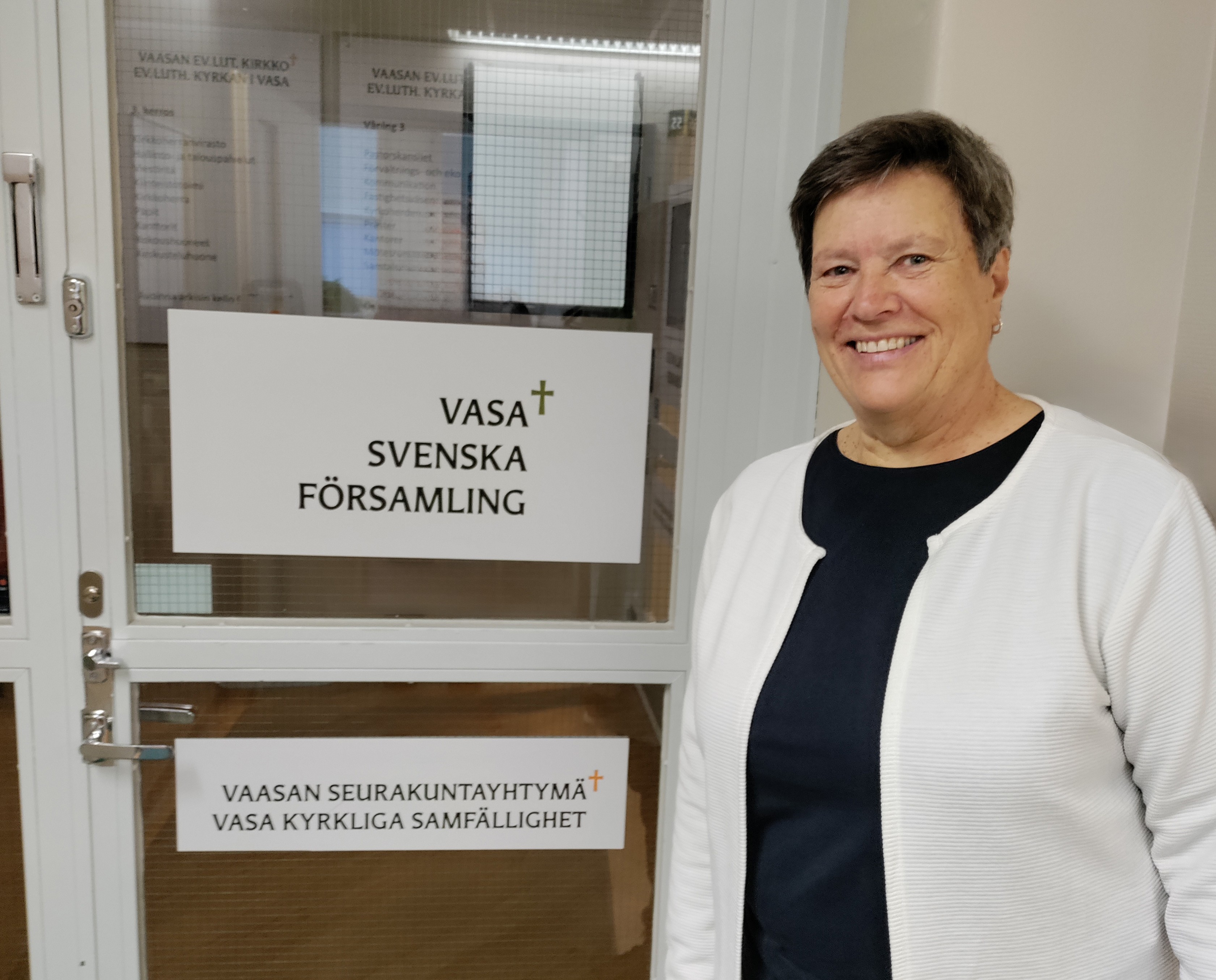 Mona Engsbo står framför en dörr med skylten Vasa svenska församling.