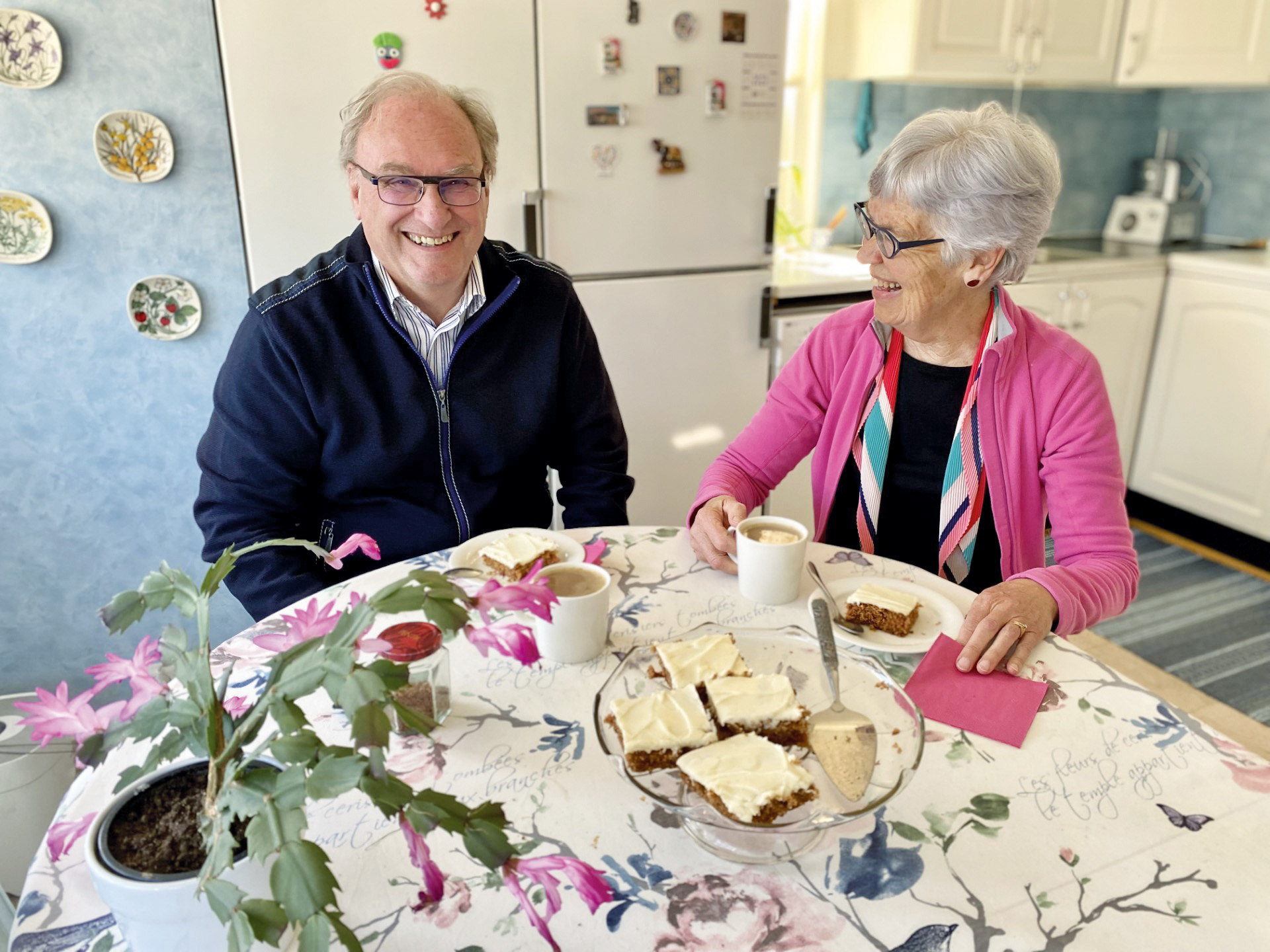 En man och kvinna sitter vid ett dukat bord i ett kök.