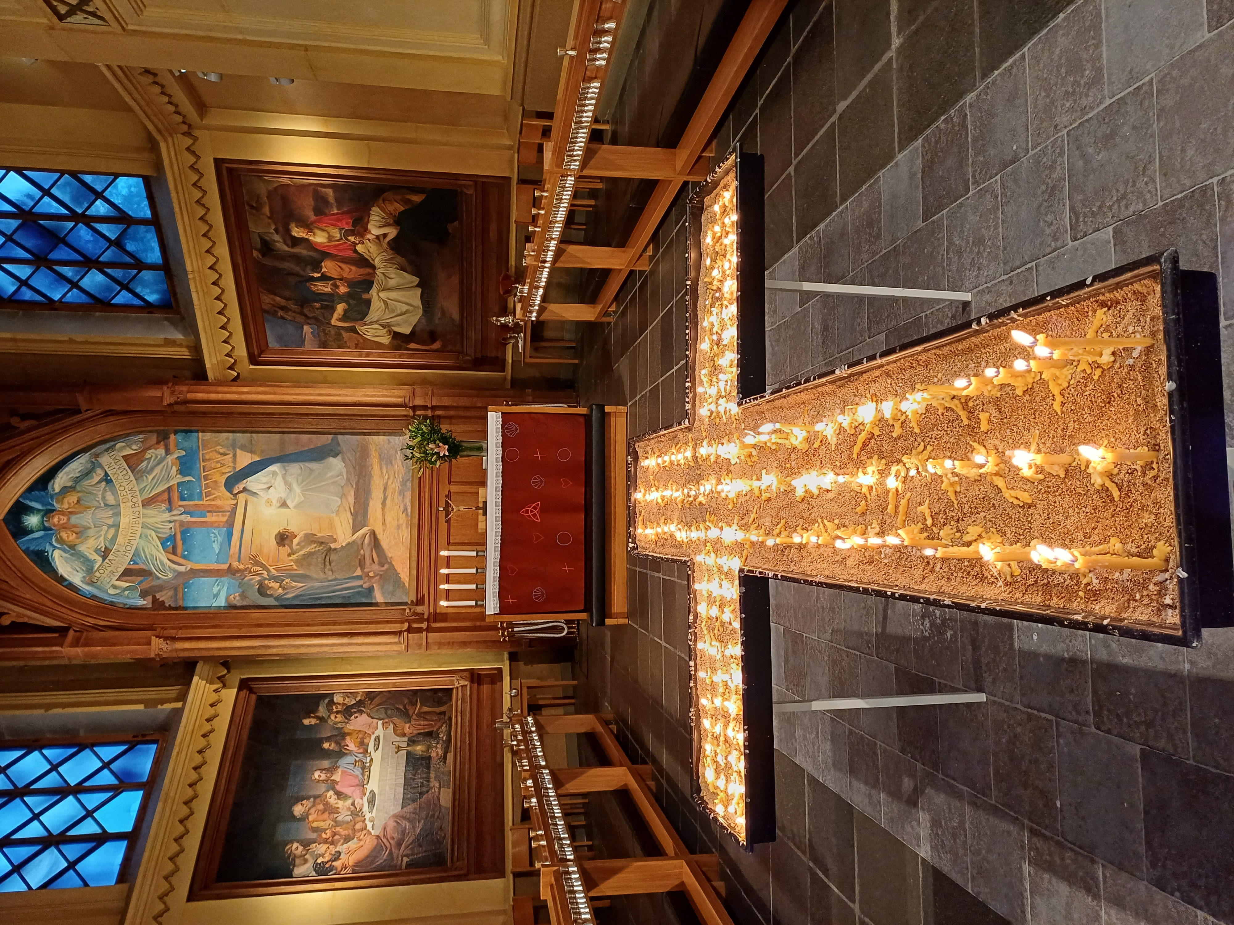 Ljus som brinner i en korsformad form framför ett altare i en kyrka.