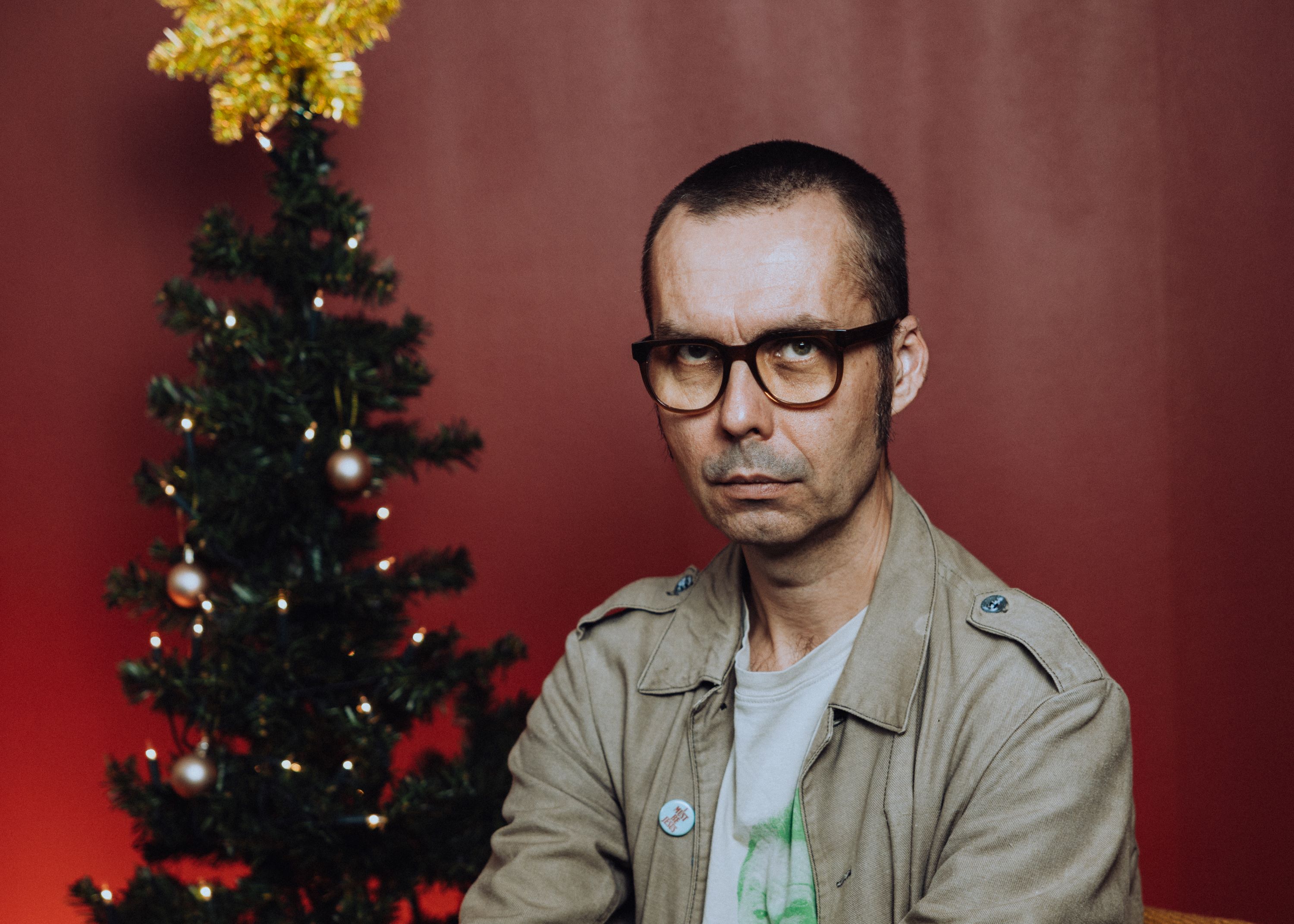En allvarlig man sitter framför en liten julgran.