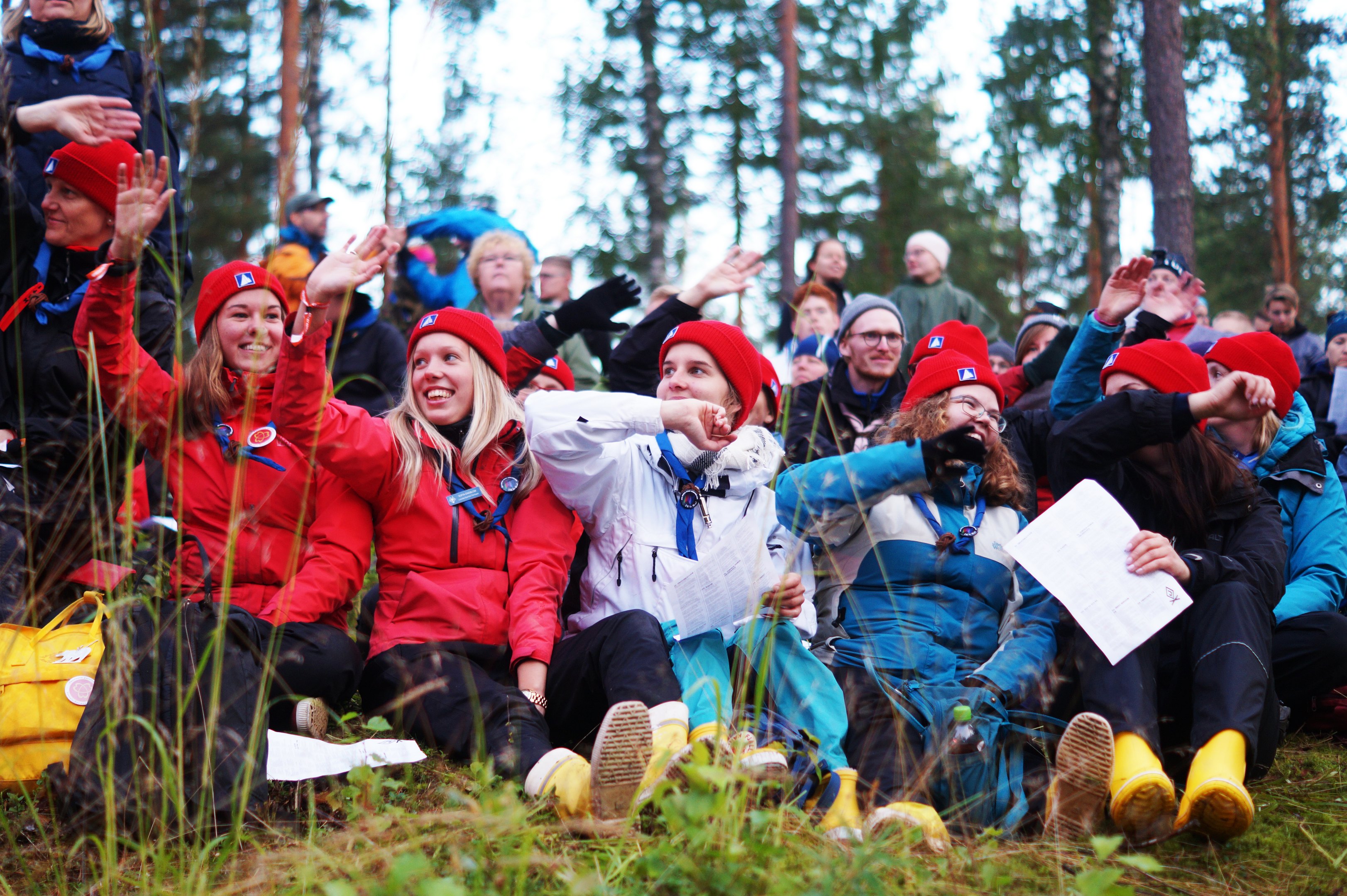 Många ungdomar sitter tillsammans i skogen.