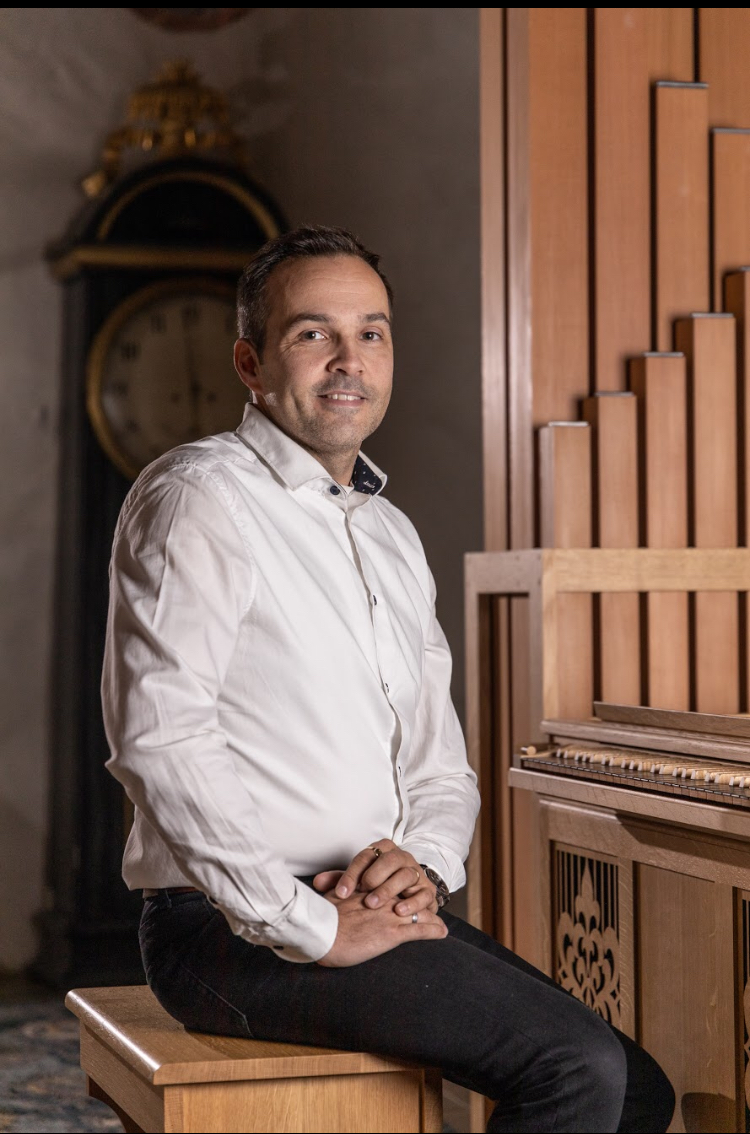 Man som sitter framför en orgel.