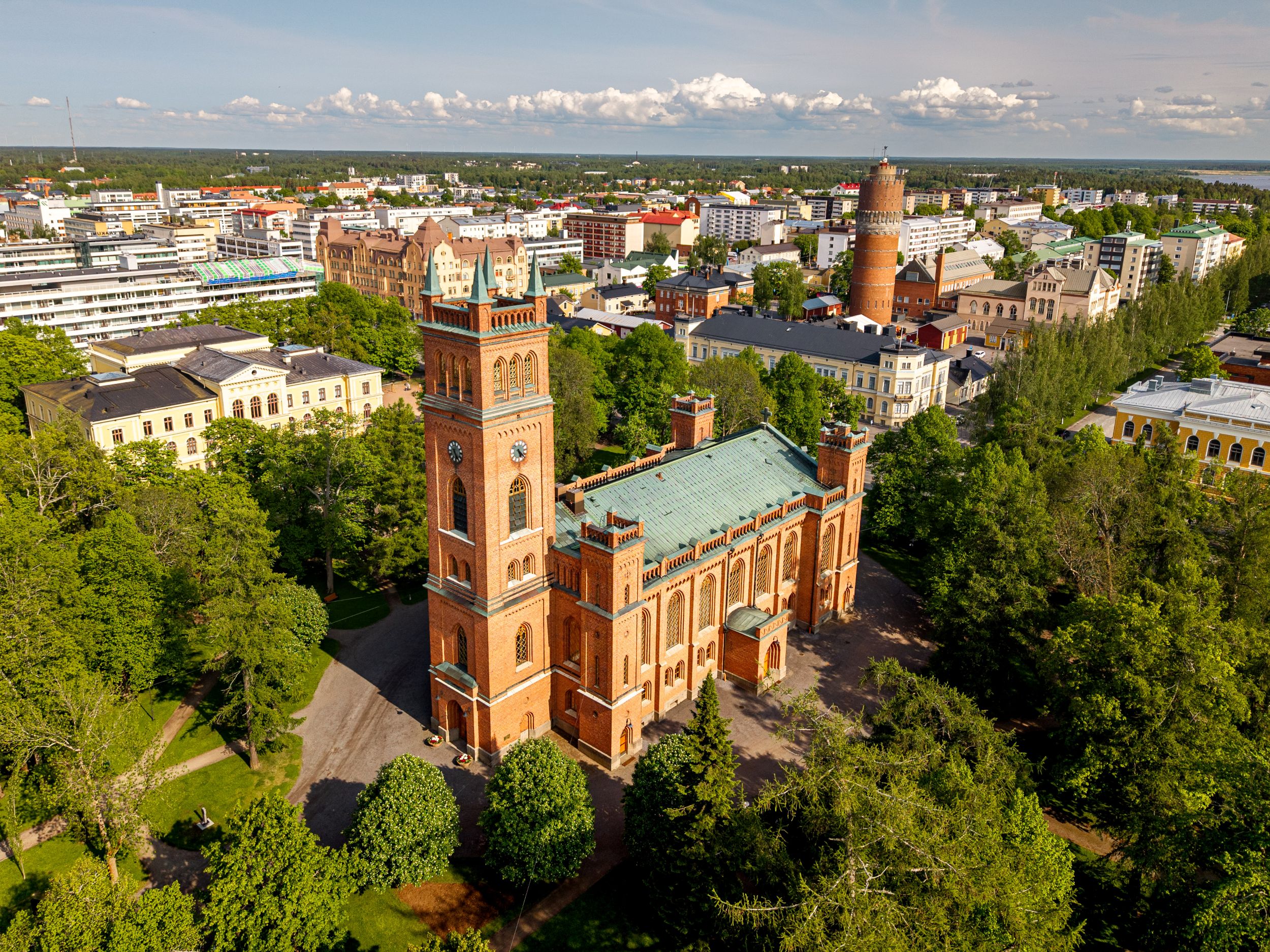 Röd stor tegelkyrka i en stad.